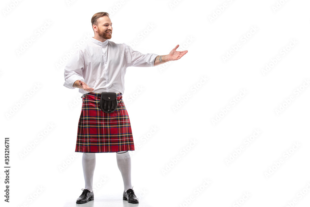 smiling Scottish redhead man in red kilt gesturing on white background smiling Scottish redhead man in red kilt gesturing on white background