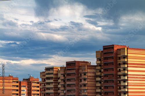 Modern brick buildings city view against cloudy blue sky 
