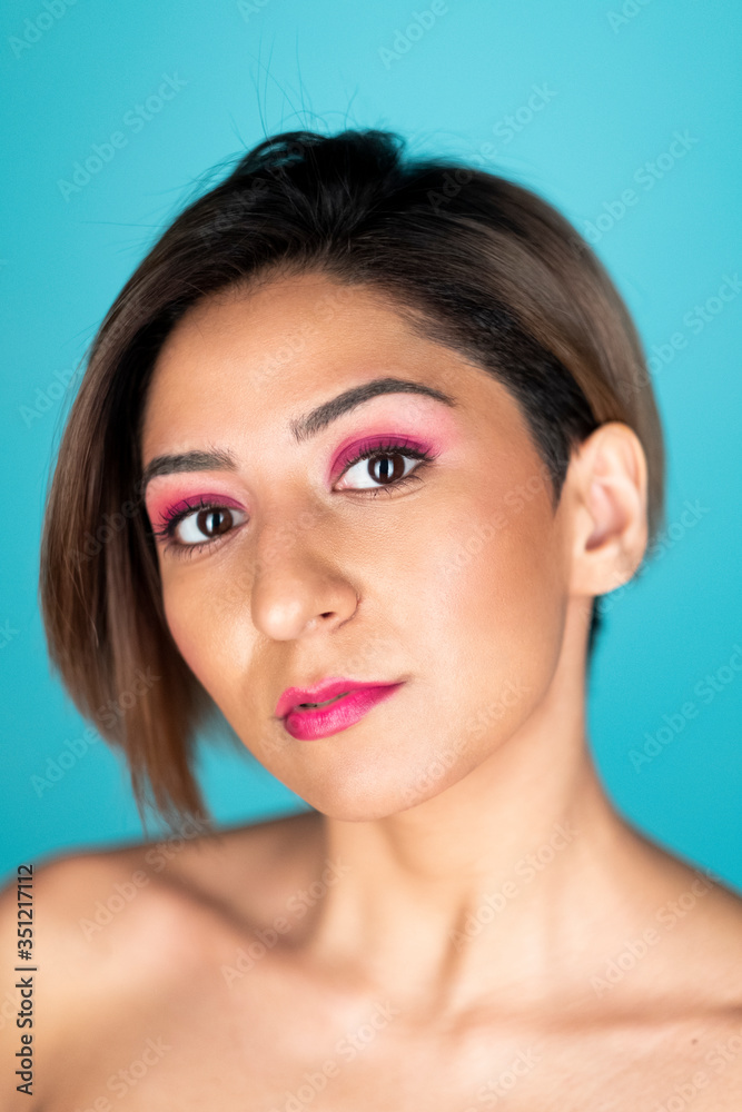Looking at camera portrait of a beautiful woman with soft skin on a blue background Looking at camera portrait of a beautiful woman with soft skin on a blue background