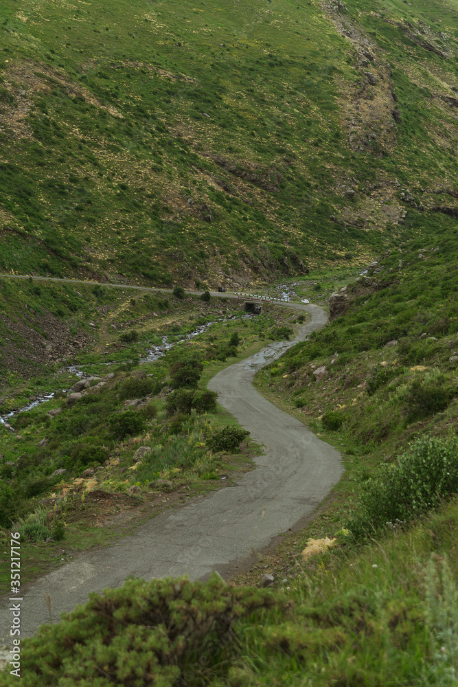 Winding paved road in mountains. From above of rural curved road in hilly area