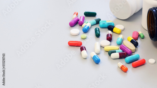 White and Brown glass medicine bottles with colorful tablets, pills, capsules drugs using for treatment and cure the disease or sickness. Drug prescription for medication isolate in white background.