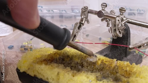 Extreame close-up of a craftsman's hand soldering two wires. The soldering process in the workshop. photo