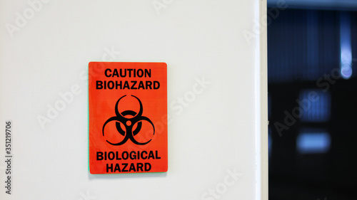 The Caution sign "Biological Hazard” for warning inflected biohazard area, a safety sign warning on white wall in laboratory room, useful for caution who working in microbiology medical science room.