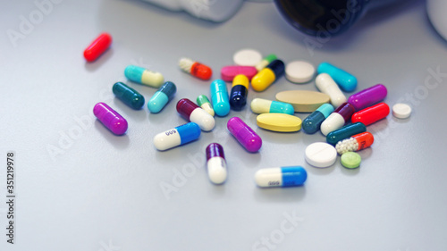 White and Brown glass medicine bottles with colorful tablets, pills, capsules drugs using for treatment and cure the disease or sickness. Drug prescription for medication isolate in white background.