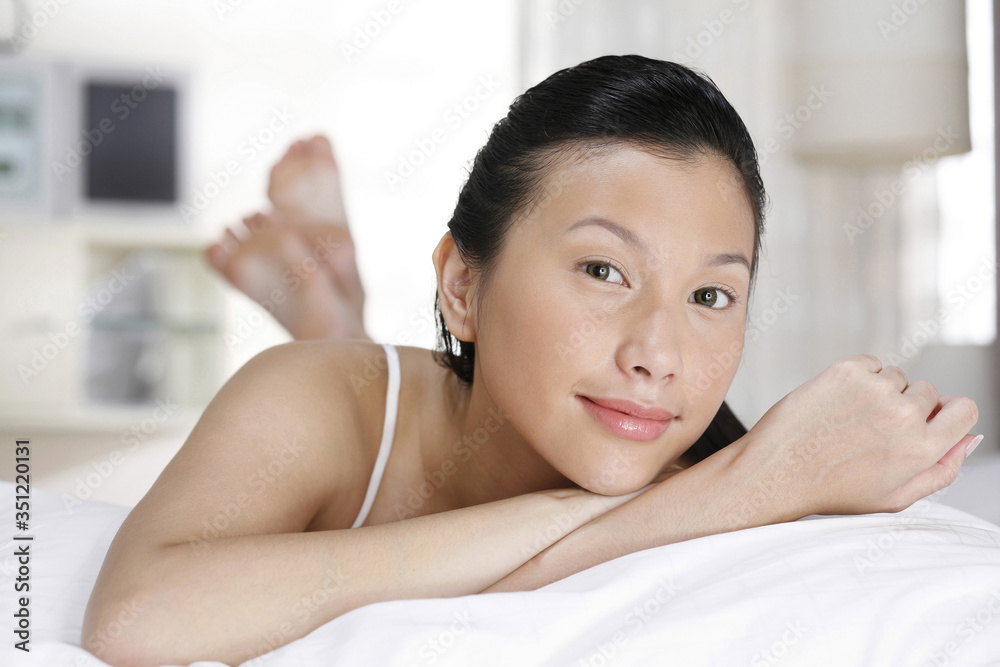 Woman lying forward on the bed, smiling at the camera Woman lying forward on the bed, smiling at the camera