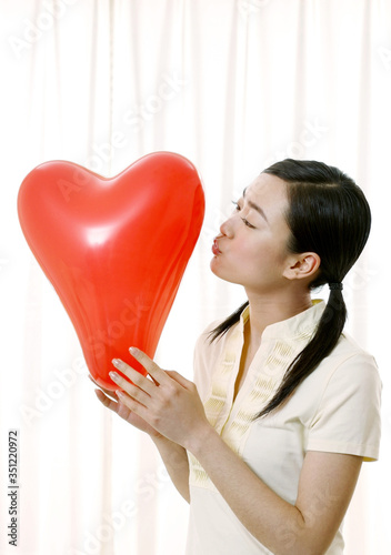 Canvas Print Woman about to kiss a heart shaped balloon