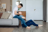 couple in home made clothes. lean on a sofa, sit on a warm wooden floor, spend time together with your beloved.