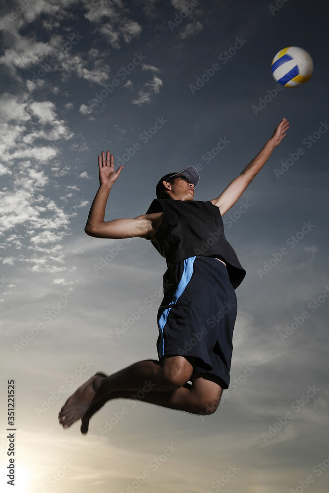 Man reaching up to hit volleyball
