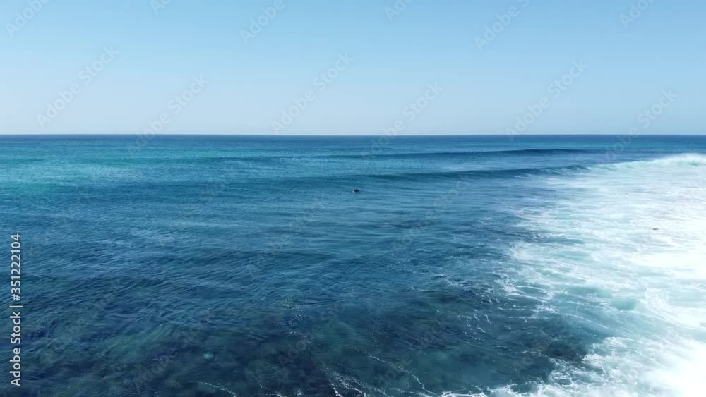 A surfer paddling out in between some waves at PontaPreta in CaboVerde, sunny weather (Drone shot) A surfer paddling out in between some waves at PontaPreta in CaboVerde, sunny weather (Drone shot)