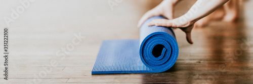 Yogi rolling her blue yoga mat