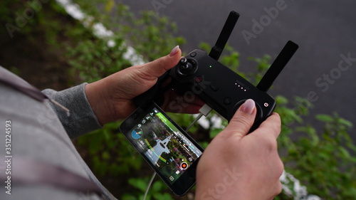 Woman operating a drone using a remote controller. Close up picture. The picture on the phone. View from above