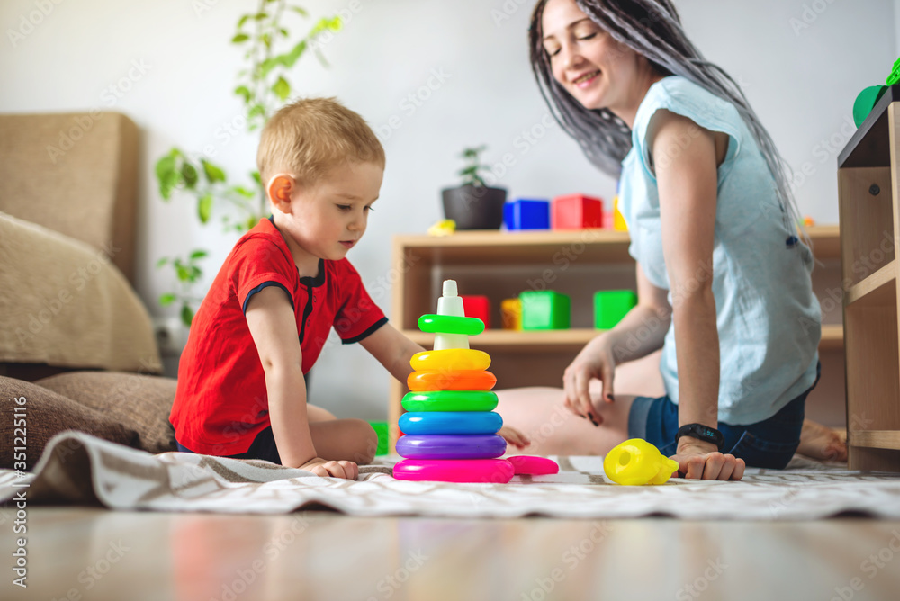 Happy mom and her child together collect a pyramid. Concept of playing with kids, spending time at home with the family Happy mom and her child together collect a pyramid. Concept of playing with kids, spending time at home with the family
