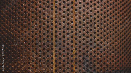 Old and rusty metal plate with circular perforations. Background.