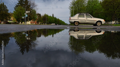Car in the reflection of the puddle. Traffic. Close-up