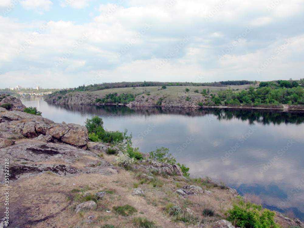 Panorama of the old Dnieper riverbed surrounded by high rocky shores on the outskirts of the city on a background of cloudy blue sky. Panorama of the old Dnieper riverbed surrounded by high rocky shores on the outskirts of the city on a background of cloudy blue sky.