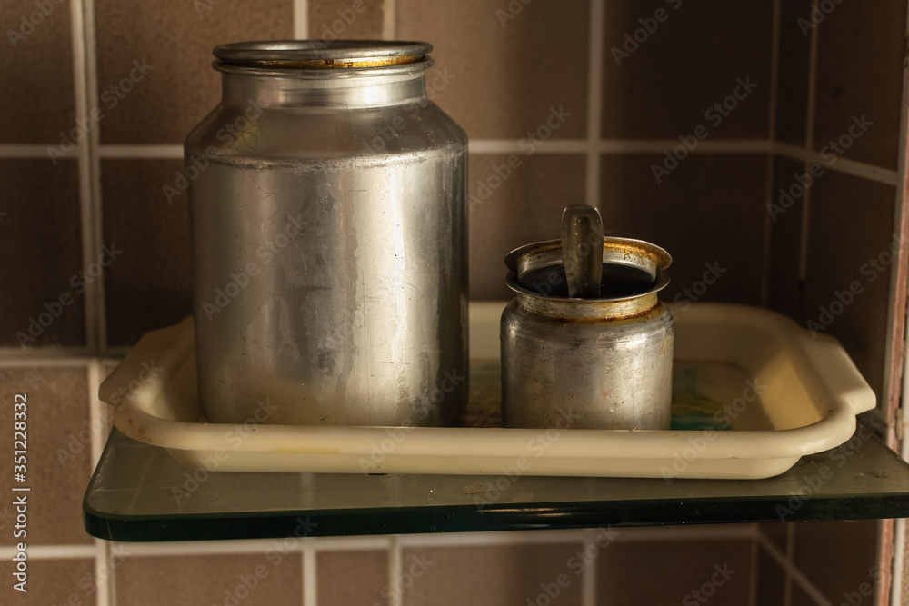 Two small metal cans to store oil on a shelf inside a kitchen. Two small metal cans to store oil on a shelf inside a kitchen.