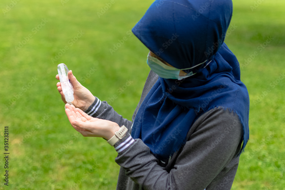 Muslim woman pouring liquid sanitizer on her hands Muslim woman pouring liquid sanitizer on her hands
