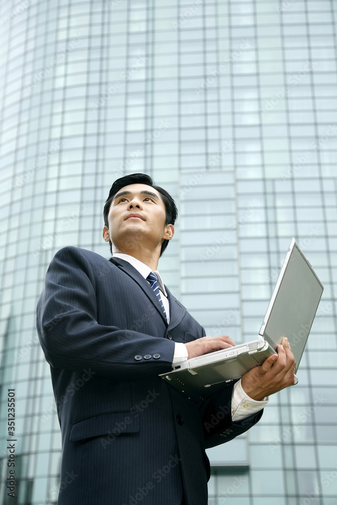 Businessman looking away while using laptop Businessman looking away while using laptop
