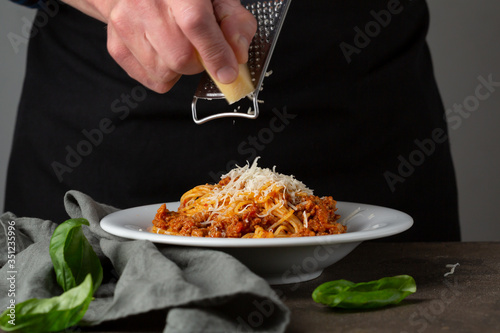 Bolognese pasta. Hand grating cheese on spaghetti photo