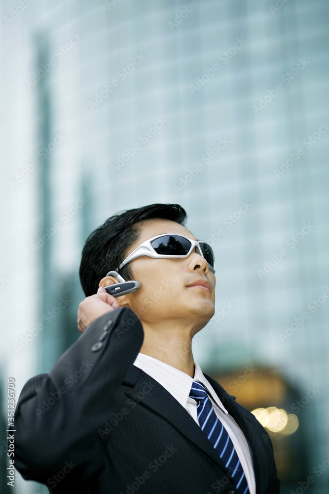 Businessman with sunglasses talking on hands-free device Businessman with sunglasses talking on hands-free device