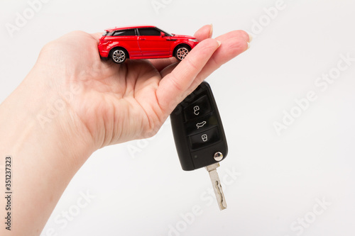 Red toy car and keys in hand isolated on white background