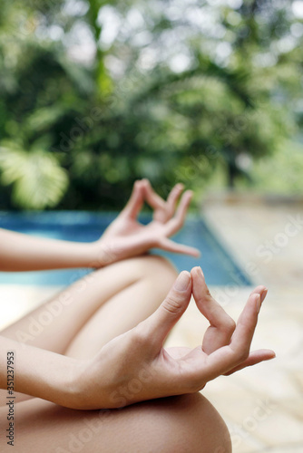 Woman meditating by the poolside