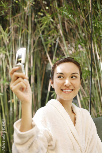 Woman in bathrobe talking picture with mobile phone
