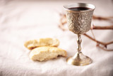 Unleavened bread, chalice of wine, silver kiddush wine cup on canva background. Communion still life. Christian communion concept for reminder of Jesus sacrifice. Easter passover