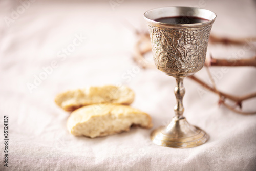 Unleavened bread, chalice of wine, silver kiddush wine cup on canva background. Communion still life. Christian communion concept for reminder of Jesus sacrifice. Easter passover