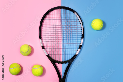 Tennis concept with balls and tennis racket on pastel pink and blue background. Top view, copy space.