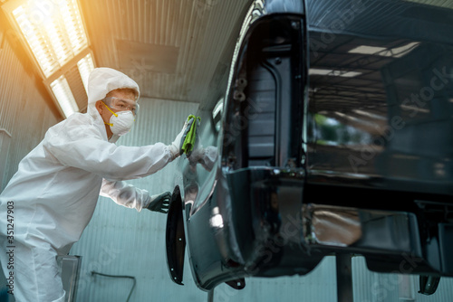 The expert is painting the car in the paint room.