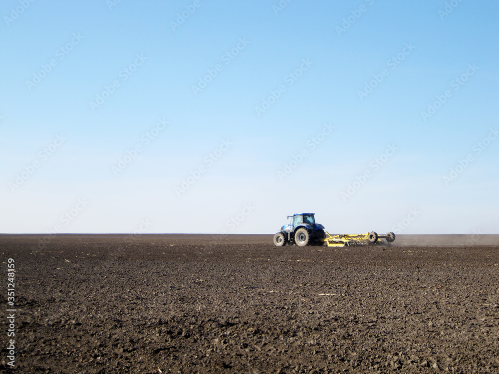 Obraz premium Plowed field by tractor in brown soil on open countryside nature