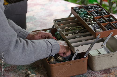 Arms of a man rummaging through a toolbox full of gardening and plumbing supplies photo