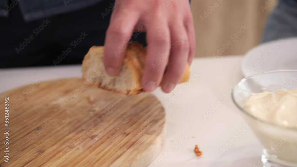 A man puts sliced baguette pieces on a white plate. A man puts sliced baguette pieces on a white plate.