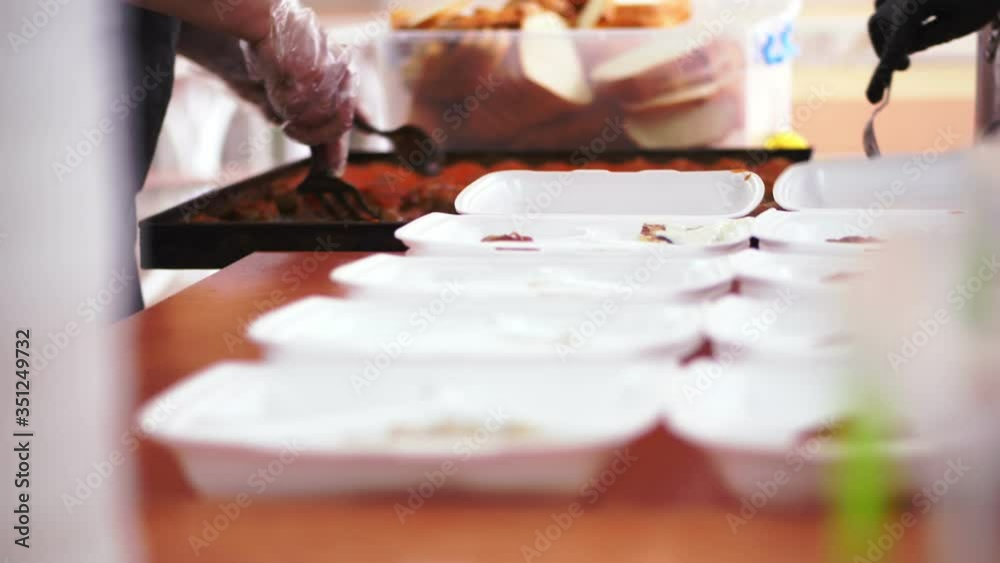 close-up, hands in disposable gloves pack Charity hot meals in lunchboxes, to be free delivered to poor people by Volunteers during lock down covid19 . food delivery. close-up, hands in disposable gloves pack Charity hot meals in lunchboxes, to be free delivered to poor people by Volunteers during lock down covid19 . food delivery.