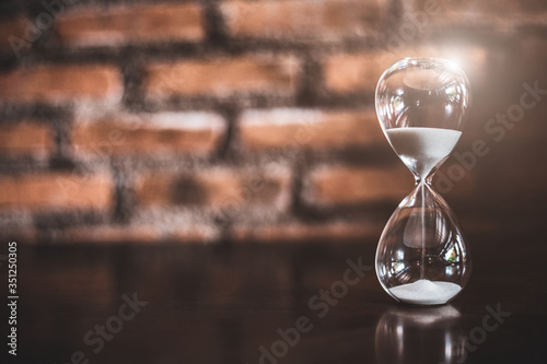 Closeup hourglass clock on brick background with copy space.