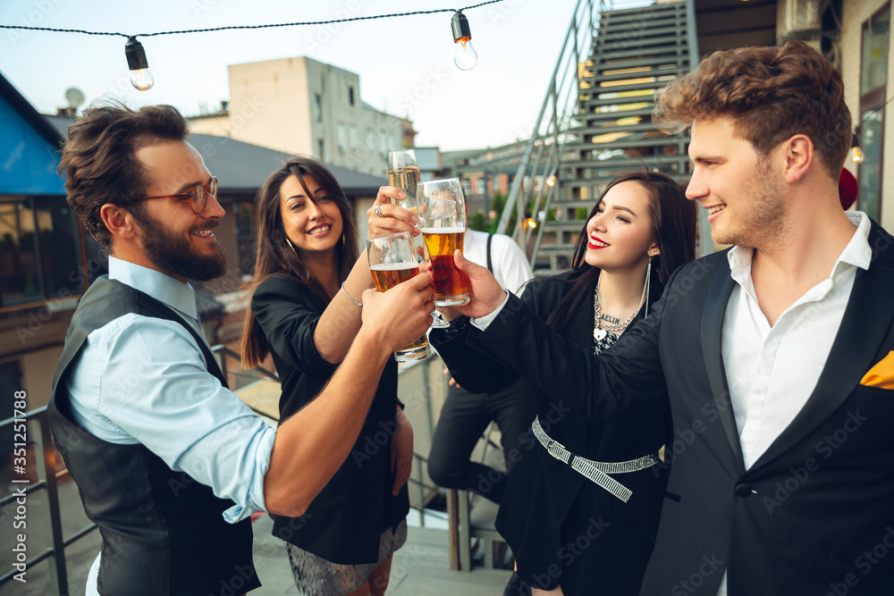 Success. Young people celebrating, look happy, have party at office or bar. Men and women drinking alcohol, talking, laughting. Holidays, weekend, business and finance, friendship concept Success. Young people celebrating, look happy, have party at office or bar. Men and women drinking alcohol, talking, laughting. Holidays, weekend, business and finance, friendship concept