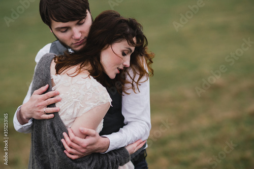 Romantic, young and happy caucasian couple in wedding clothes hugging on the background of beautiful mountains. Love, relationships, romance, happiness concept. Bride and groom traveling together.