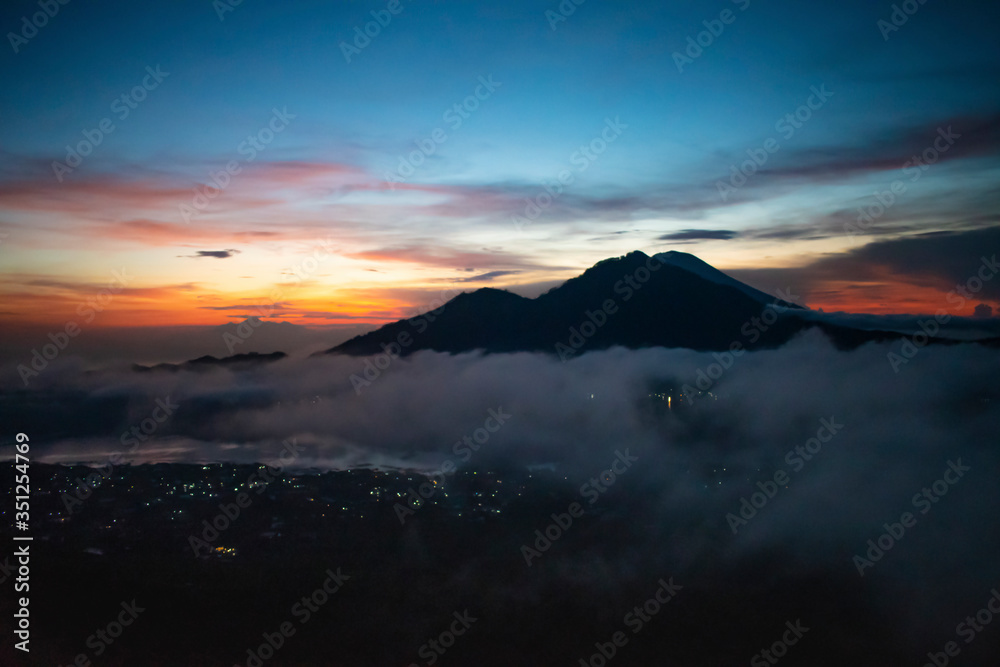 A spectacular landscape view of kintamani volcano and golden sky from the top of the Mount Batur during the sunrise with fog