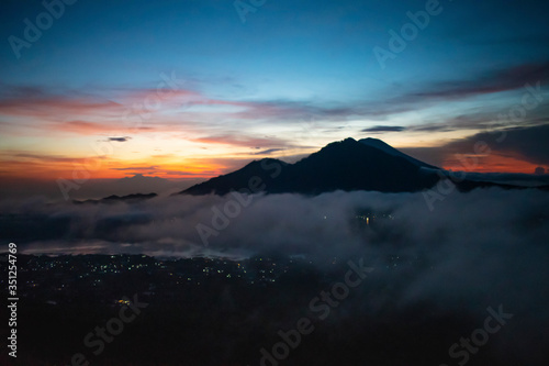A spectacular landscape view of kintamani volcano and golden sky from the top of the Mount Batur during the sunrise with fog © Souvik
