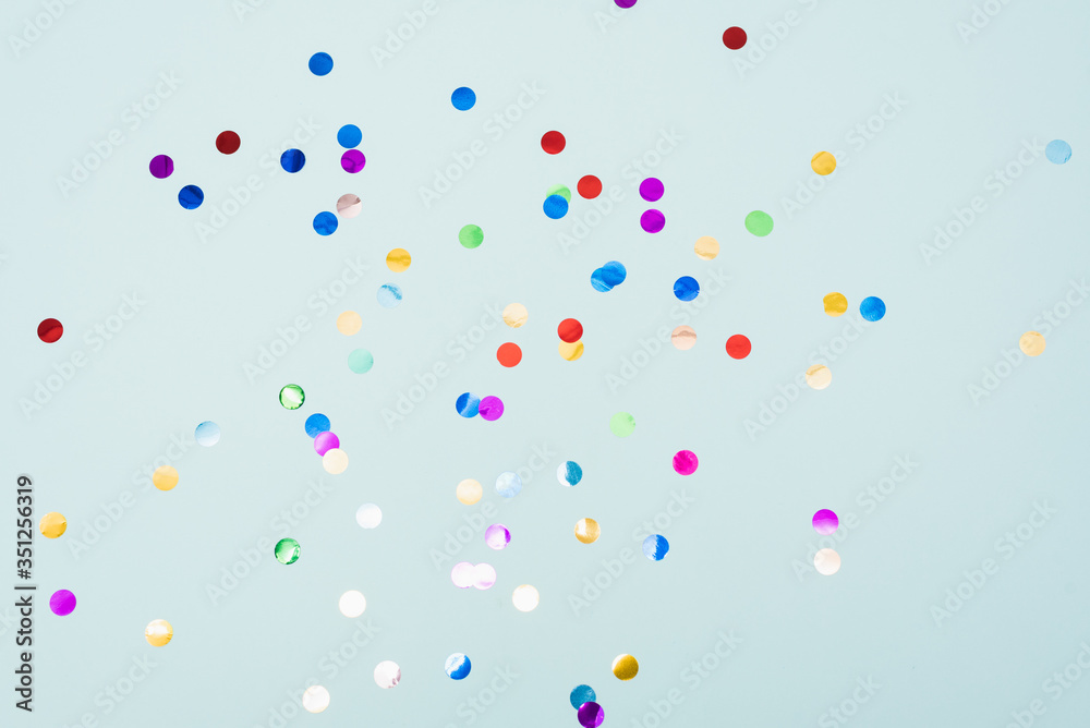 Confetti scattered on the light blue background. Bright dots on the background. - obrazy, fototapety, plakaty 