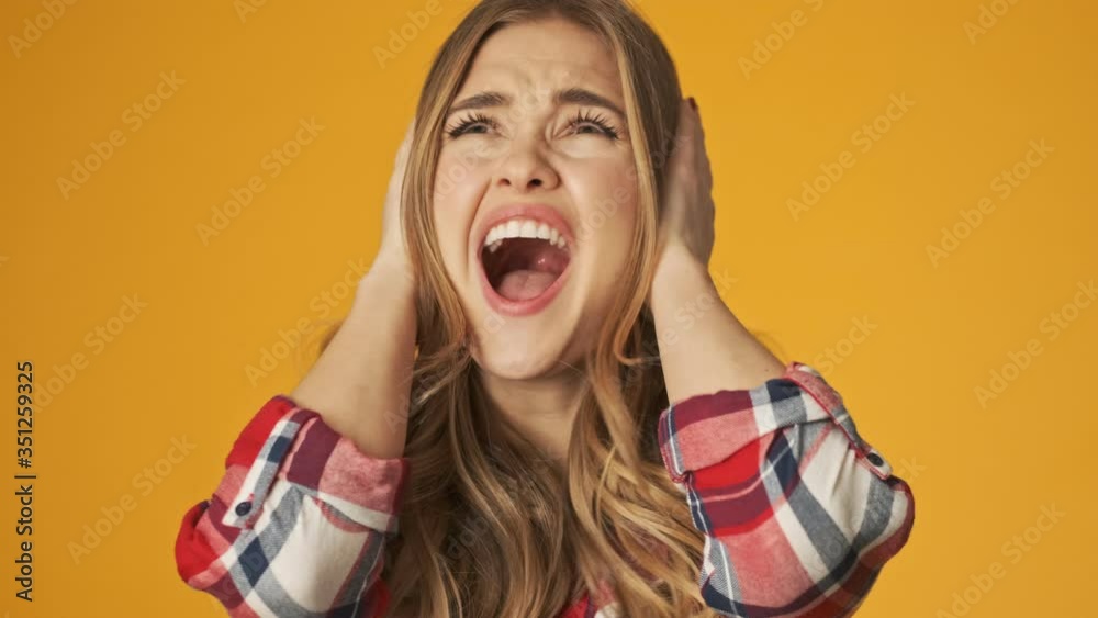 Young stressed screaming girl isolated over yellow wall background