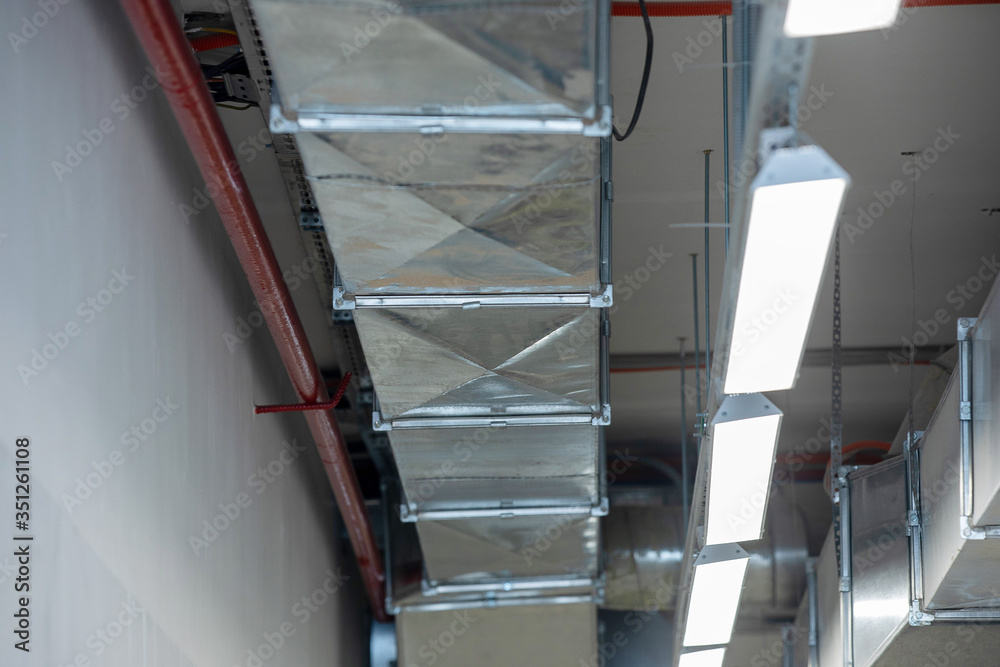 Obraz premium New installation of steel air conditioning duct pipes and lighted dumps, installation of ventilation ducts during the renovation of building.
