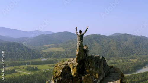 Man standing with raised hands on the top of Mountain Devil's finger peak. Altai