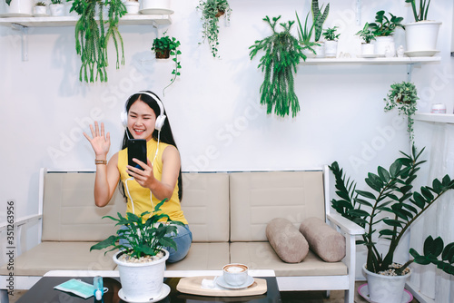 Beautiful Asian women in cafes are enjoying video chatting on their mobile phones. She uses the video-to-face system. Concept of an Asian woman using an online video conference system