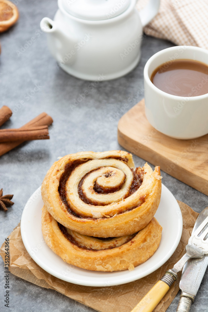 Cinnamon roll bun close up. Cinnamon swirl pastry for breakfast over grey background. Cinnamon roll bun close up. Cinnamon swirl pastry for breakfast over grey background.