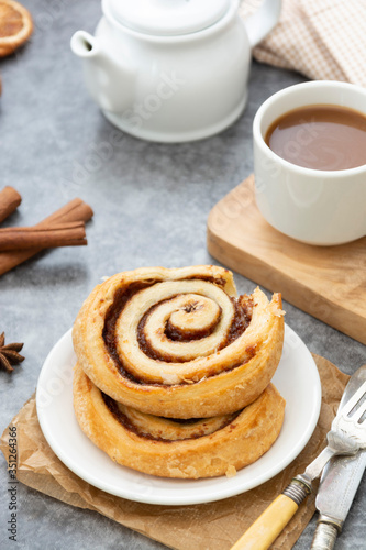 Cinnamon roll bun close up. Cinnamon swirl pastry for breakfast over grey background. © Inga