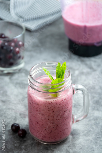 Fresh fruit berry smoothie in glass jar with mint leaves, grey background. Detox, summer drink.