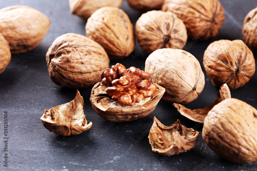 Walnut kernels and group of whole walnuts on rustic old table Walnut kernels and group of whole walnuts on rustic old table