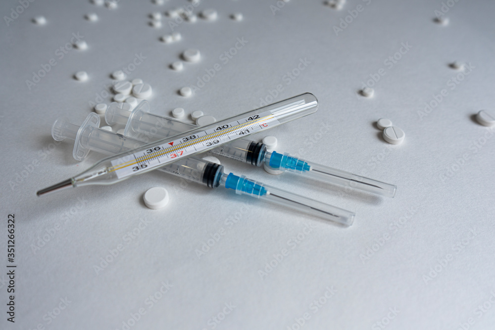 thermometer lies on a syringe in the background of a tablet thermometer lies on a syringe in the background of a tablet